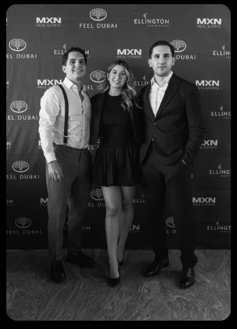 Alexis Abascal con dos asistentes frente al backdrop de MXN Real Estate, Feel Dubai y Ellington Properties.