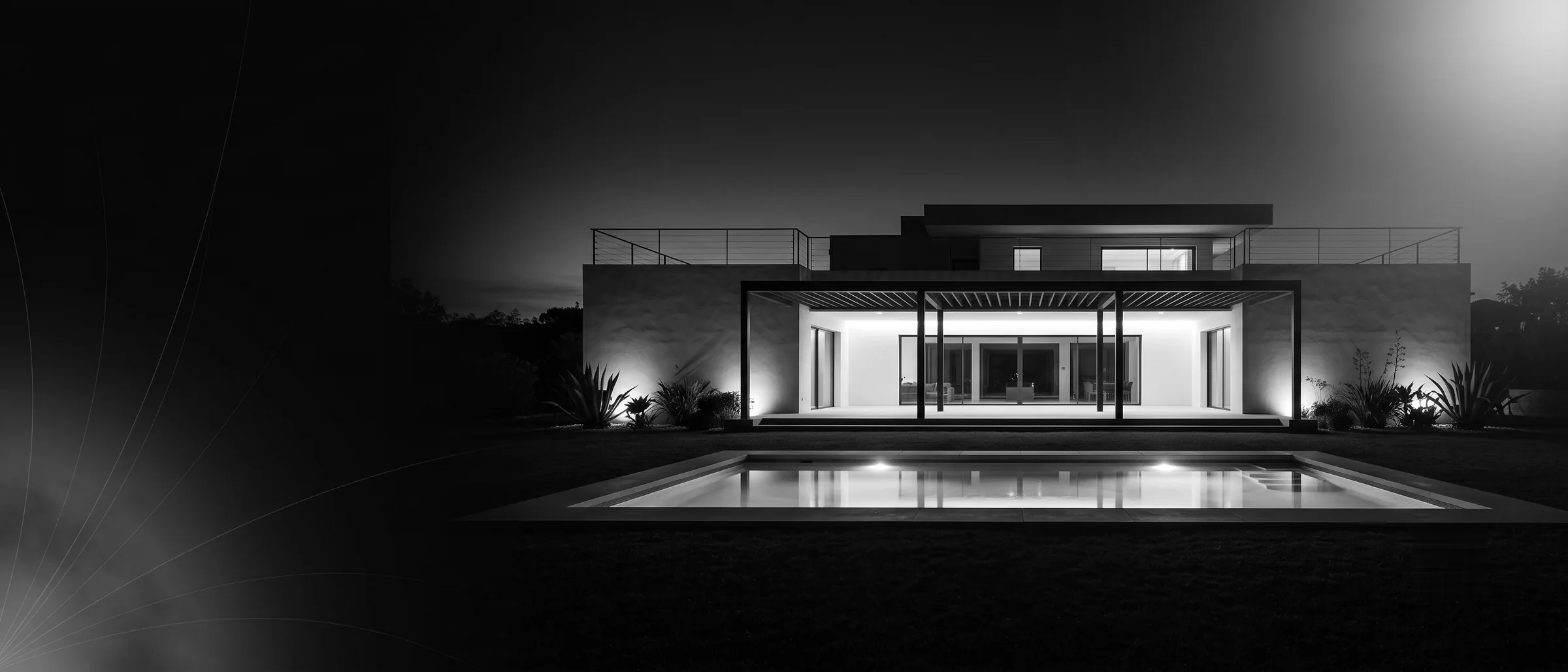Residencia contemporánea del desarrollo Privanza Habitat fotografiada de noche, con la terraza iluminada reflejándose en la alberca.