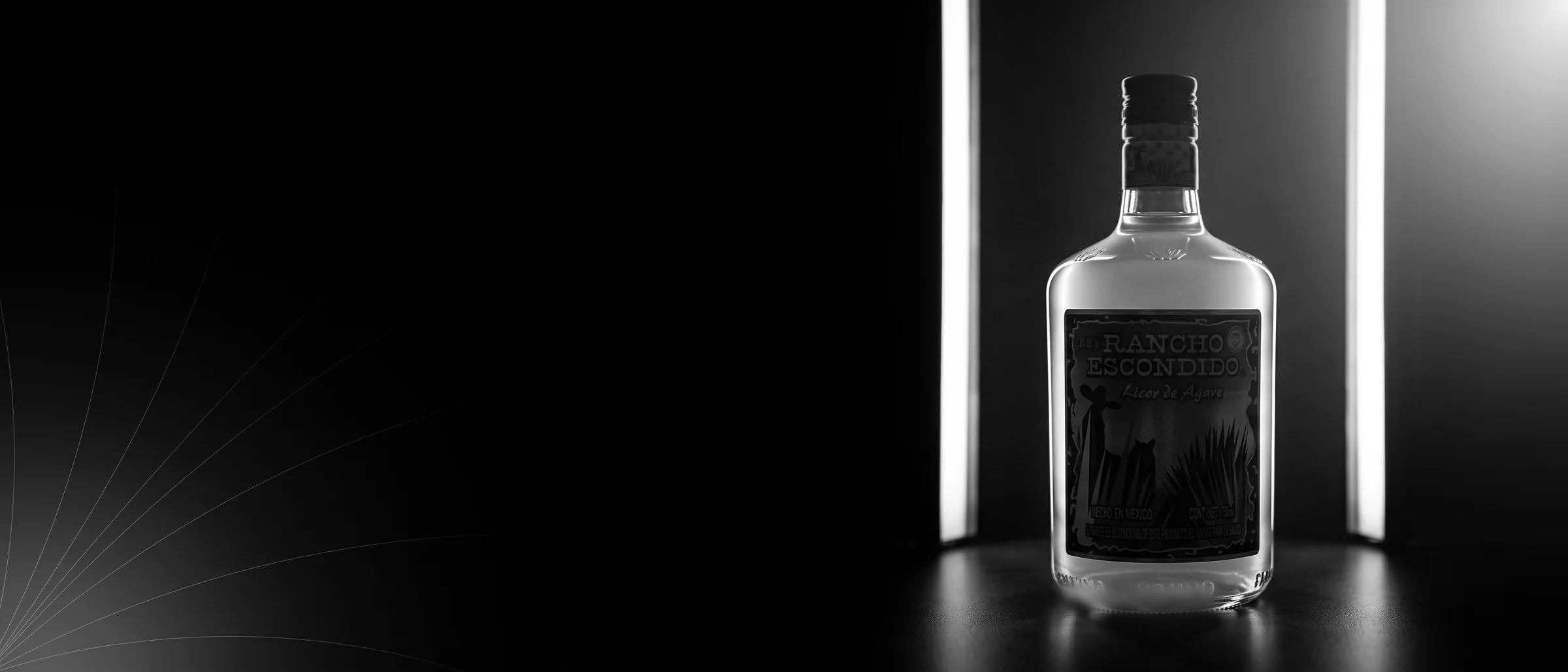 Botella de licor de agave Rancho Escondido iluminada en estudio con luz de contorno sobre fondo negro.